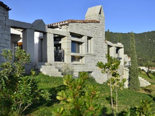 a stone house on a hill with grass and trees at Case Li Conchi Sardegna in Castiadas
