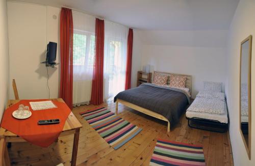 a bedroom with a bed and a table in it at Pensiunea Tiuta in Corbeni