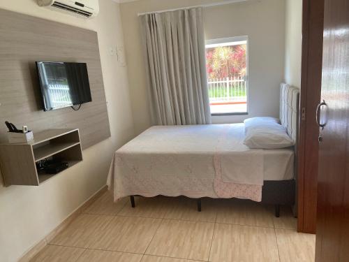 een slaapkamer met een bed, een tv en een raam bij Residencial Cecilia Cruz in Bombinhas
