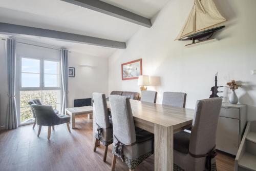 een eetkamer met een houten tafel en stoelen bij PERTUIS appartement tout confort in Landrais