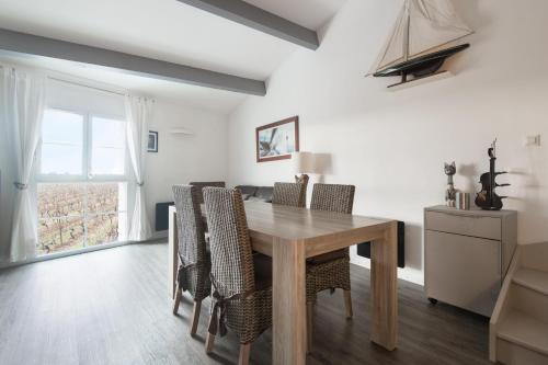 een eetkamer met een houten tafel en stoelen bij PERTUIS appartement tout confort in Landrais