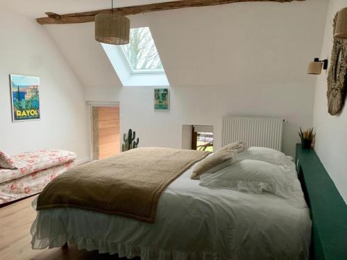 Schlafzimmer mit einem großen Bett und einem Dachfenster in der Unterkunft La MIDAD in La Chapelle-Thècle