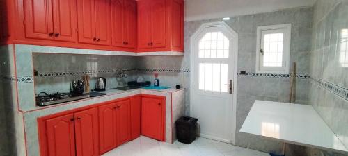 - une cuisine avec des placards rouges et un évier blanc dans l'établissement Villa Jasmine "Serenity Oasis", à Agadir