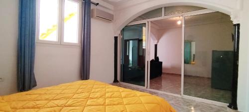 a bedroom with a yellow bed and a glass shower at Villa Jasmine "Serenity Oasis" in Agadir