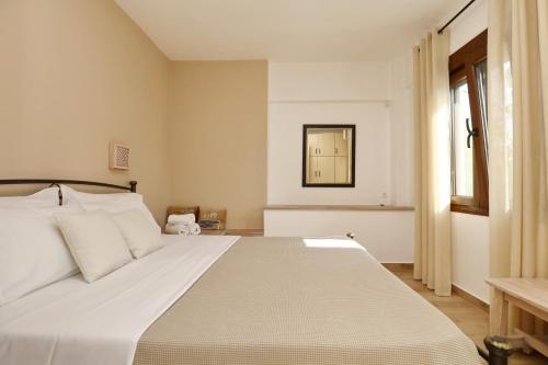 a bedroom with a large white bed with a window at Diakopi Villa in Skopelos Town