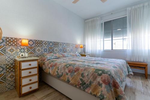 una camera con letto, comodino e finestra di rentafive 8pax Terraza 1min playa a Santa Pola