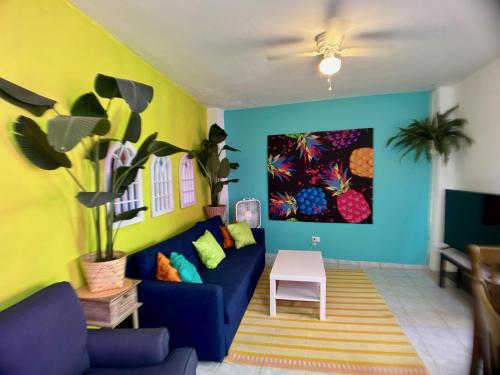 - un salon avec un canapé bleu et un mur jaune dans l'établissement Casa Lima in Villa Palmeras, à San Juan