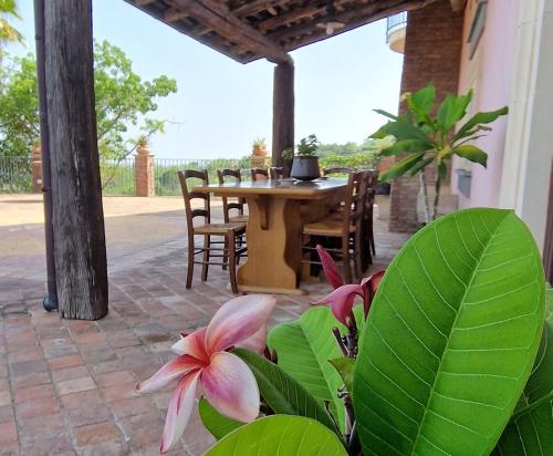 a patio with a table and chairs and a flower at VILLA PANORAMICA DELL'ETNA in SantʼAlfio