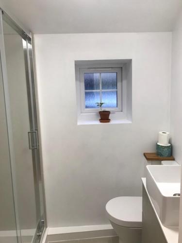 a white bathroom with a toilet and a window at The Old Police House in Cheddar