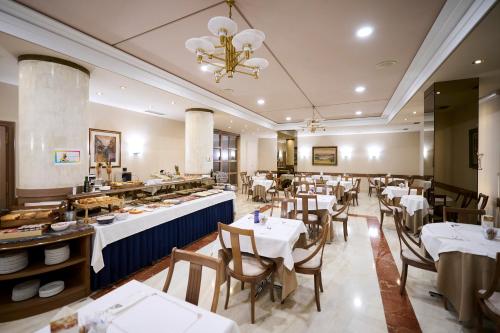 パンプローナにあるホテル アルブレトのテーブルと椅子のあるレストラン、ビュッフェ