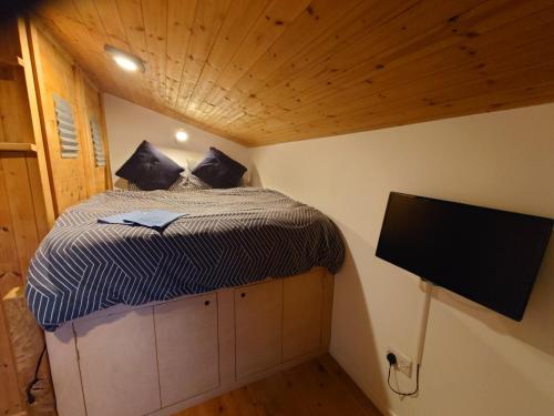 a small bedroom with a bed and a flat screen tv at Fern Cottage Annexe in Croyde