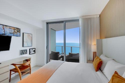 哈蘭代爾海灘的住宿－2 BR Beach condo ocean views at Hyde MIiami，配有一张床、一张书桌和一扇窗户的酒店客房