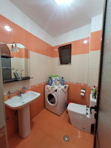 uma casa de banho com uma máquina de lavar roupa e um lavatório em Guesthouse Kocibelli em Korçë