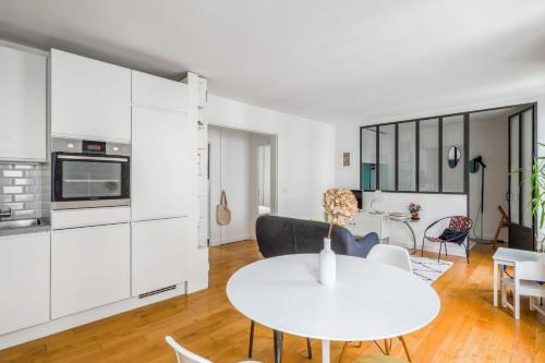 eine Küche und ein Wohnzimmer mit einem weißen Tisch und Stühlen in der Unterkunft Nice T3 near Lake Saint-Mandé - Welkeys in Saint-Mandé