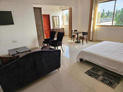 a bedroom with a bed and a couch and chairs at Hotel Kilimanjaro in Luanda