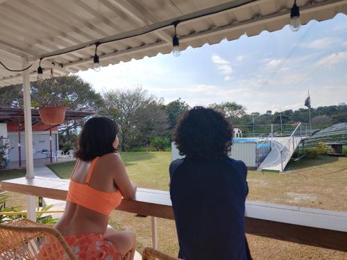 two women sitting on a bench looking out of a window at Dreamcatcher House Bus Experience 2 in Sarchí