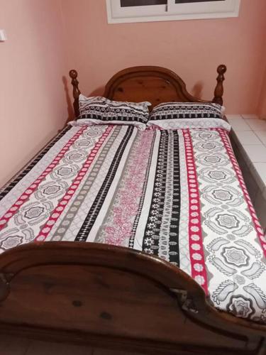 un letto in legno con una trapunta colorata sopra di Vacances agréables c'est ici a Les Abymes