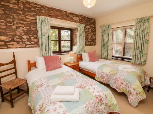 1 dormitorio con 2 camas y pared de piedra en Barn Owl, en Clatworthy