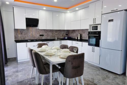 biała kuchnia z białym stołem i krzesłami w obiekcie Villa Grand Yaşar-3 w mieście Muğla