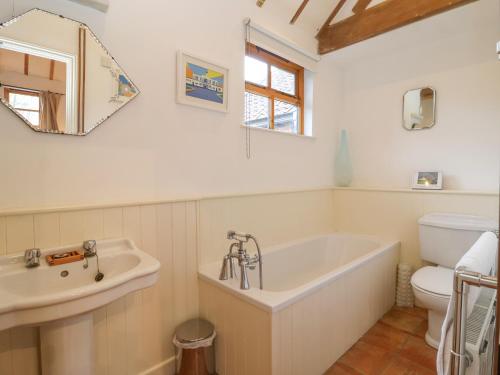uma casa de banho com uma banheira, um lavatório e um WC. em Packway Barn em Halesworth