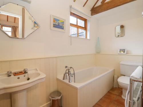 a bathroom with a tub and a sink and a toilet at Packway Barn in Halesworth