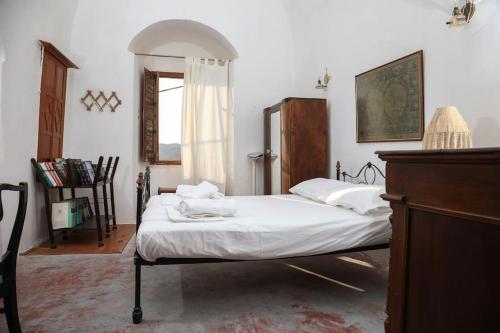 a bedroom with a bed with white sheets and a window at Tower of Dellarokas in Mélanes