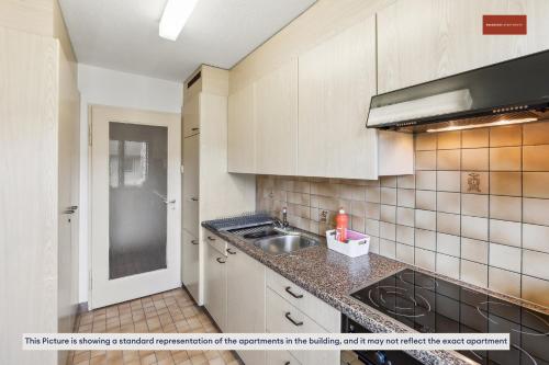 uma cozinha com armários brancos e um lavatório em Urban Living Redefined: Apartment in Oerlikon em Zurique