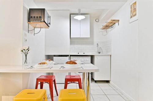 a kitchen with white cabinets and red stools at Appartement proche Canal Saint Martin in Paris