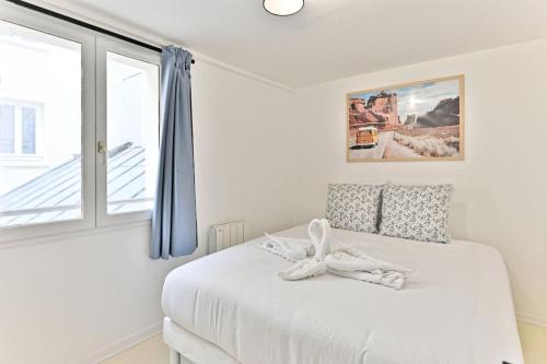 a white bedroom with a bed and a window at Appartement proche Canal Saint Martin in Paris