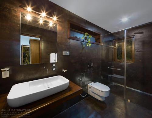ein Badezimmer mit einem Waschbecken, einem WC und einem Spiegel in der Unterkunft Villa 47 Colombo in Pannipitiya