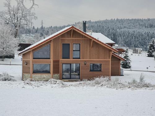 a wooden house in the snow with snow at CHALET L'ÉCHAPPÉE NATURE 4 étoiles sauna in Anould