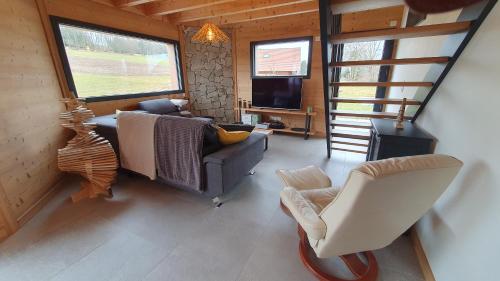 a living room with a couch and a chair at CHALET L'ÉCHAPPÉE NATURE 4 étoiles sauna in Anould
