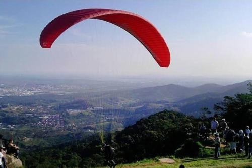 a red paraglider is flying over a mountain at casa da Déa in Mogi das Cruzes