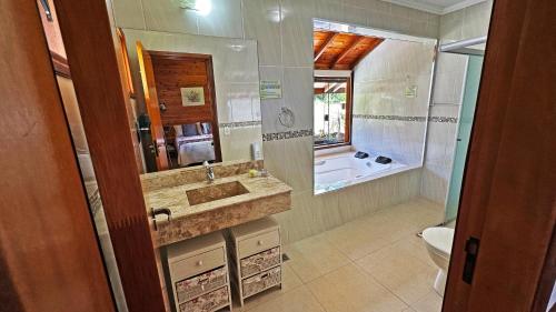 a bathroom with a sink and a toilet and a tub at Pousada Charme da Serra in Monte Verde