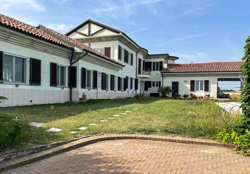 una gran casa blanca con un patio de ladrillo en Villa Bricco Astiani, en Montegrosso dʼAsti