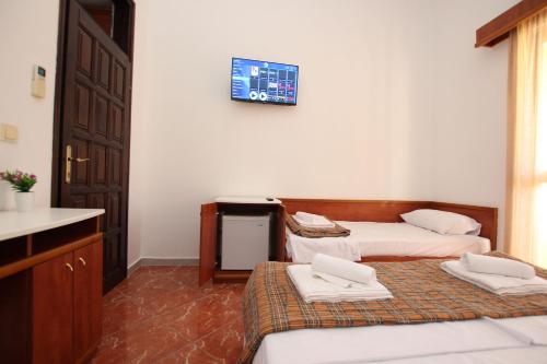 Cette chambre comprend 2 lits et une télévision murale. dans l'établissement Magnolia rooms and apartments, à Sutomore