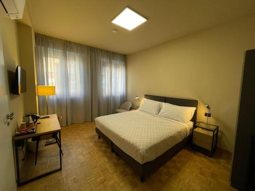 Schlafzimmer mit einem Bett, einem Tisch und einem Fenster in der Unterkunft La Galleria Lodge in Parma