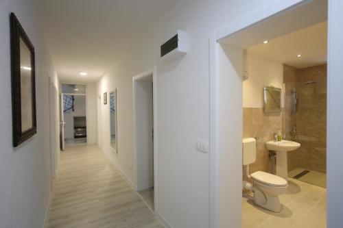 a white bathroom with a toilet and a sink at Apartments Daris in Mostar