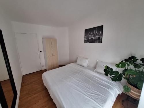 - une chambre avec un lit blanc et une plante en pot dans l'établissement MERVEILLE APP, à Suresnes