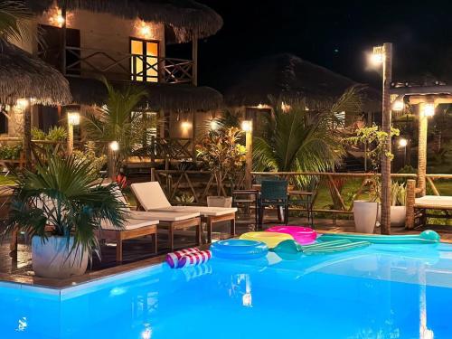 a swimming pool in front of a resort at night at Pousada Morro do Caburé in Cajueiro