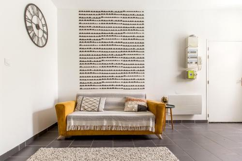 a couch in a living room with a clock on the wall at La Maison Jaurès - L'Ethnique in Liévin