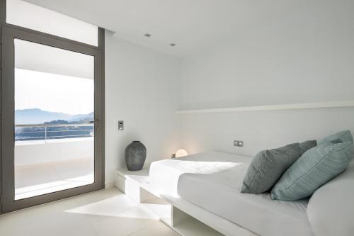 a white bedroom with a bed and a window at Buccara Altea Hills Villas in Altea
