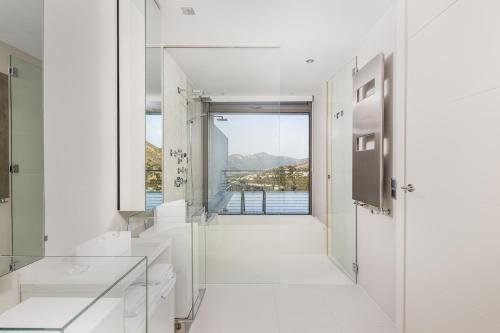 a white bathroom with a view of the water at Buccara Altea Hills Villas in Altea