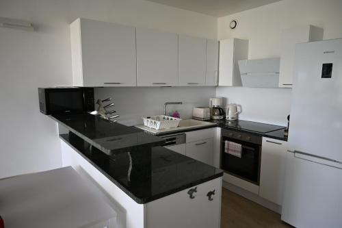 une cuisine avec des armoires blanches et un comptoir noir dans l'établissement LE DAUPHIN Climatisation Fibre 4 personnes, à Cassis