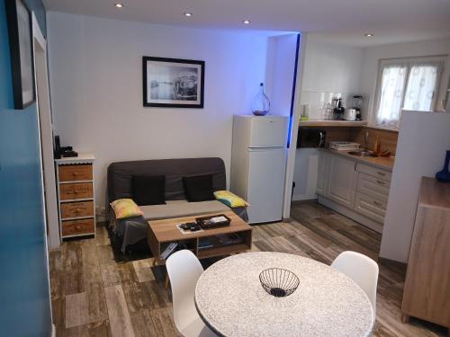 un salon avec une table et une cuisine dans l'établissement Cosy T2, Meublé de tourisme 3 étoiles, Parking fermé , 2Vélos, Wi-Fi, à Narbonne