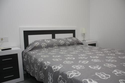1 dormitorio con cama con colcha gris y blanca en Apartamento Capri 4 Inmomart, en Peñíscola