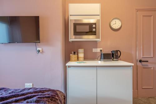 a kitchen with a counter and a clock on the wall at Boutique Home Stay Blossom in Paisley