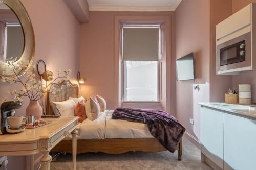 1 dormitorio con cama, escritorio y espejo en Boutique Home Stay Blossom, en Paisley