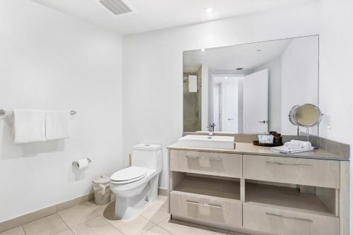 a white bathroom with a toilet and a sink at Ocean View Balcony with Pool Gym Access in Hallandale Beach