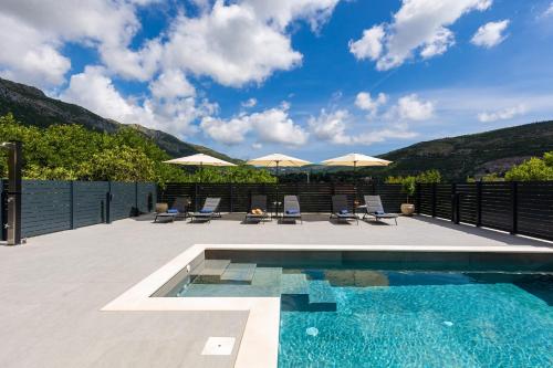 a swimming pool with chairs and umbrellas on a patio at Villa Nono in Dubrovnik